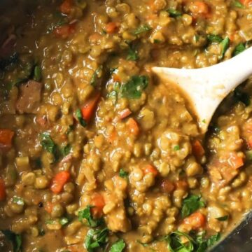 Slow cooker split pea soup in a slow cooker with a spoon.