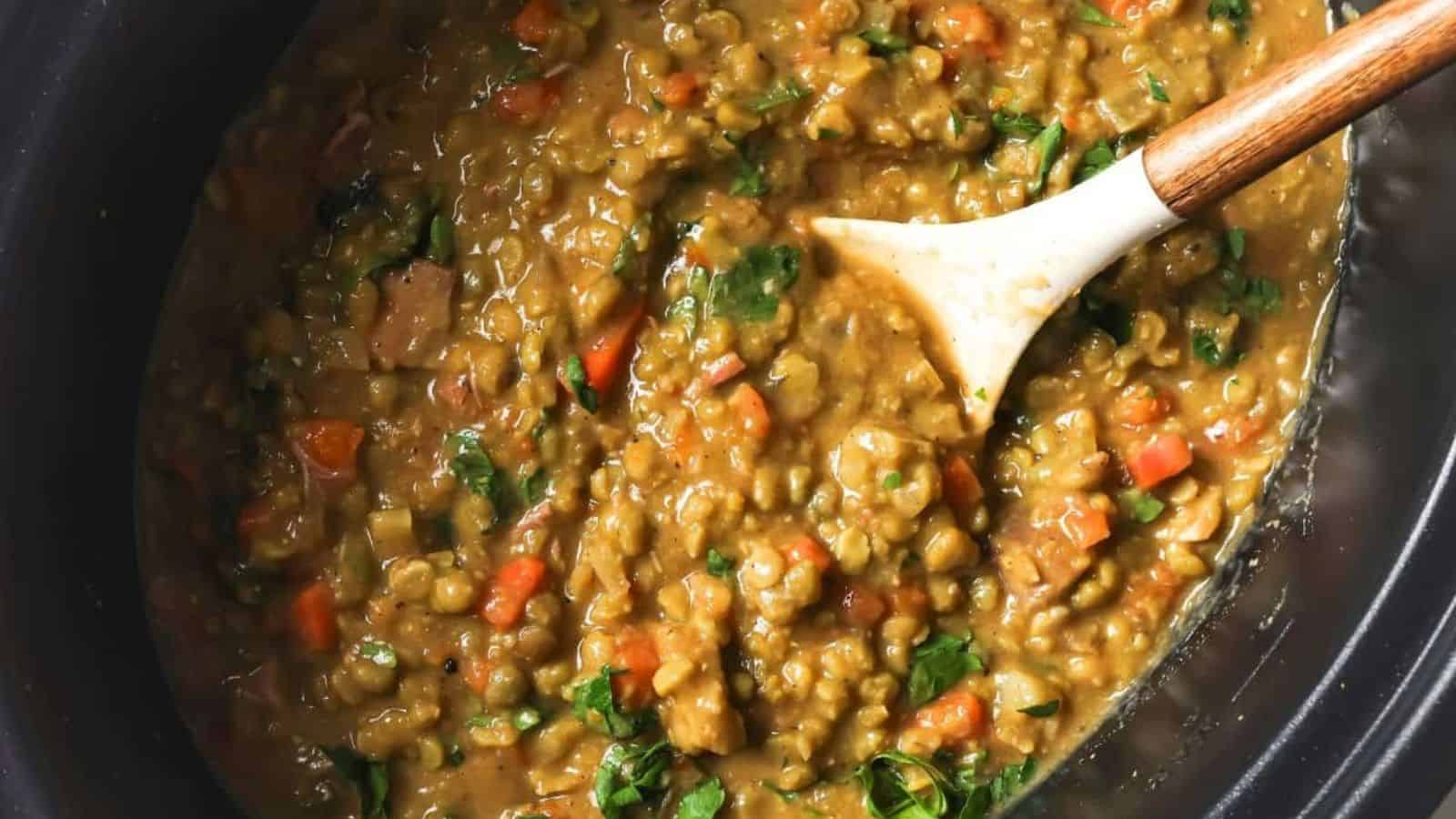 Slow cooker split pea soup in a slow cooker with a spoon.