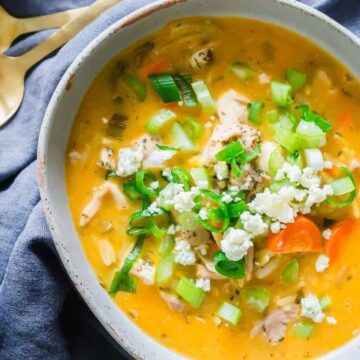 Buffalo chicken soup with orzo served in a bowl with blue cheese crumbles and green onion.
