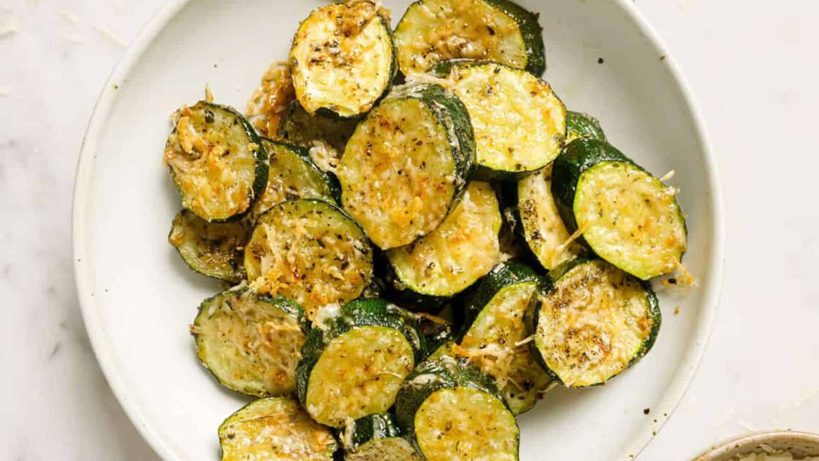 Baked sliced zucchini with parmesan on a white plate.