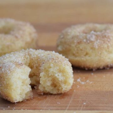 Image shows Baked cinnamon sugar donuts on a wooden table.
