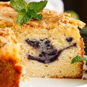A close-up of Grandma's cake on a plate, revealing a swirl of dark filling inside. The cake has a golden-brown crust and is garnished with fresh mint leaves, promising the comforting taste of cherished sweets.