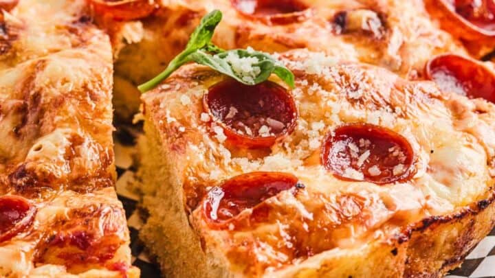 Close-up of cheesy pepperoni pizza with a garnish of fresh basil.