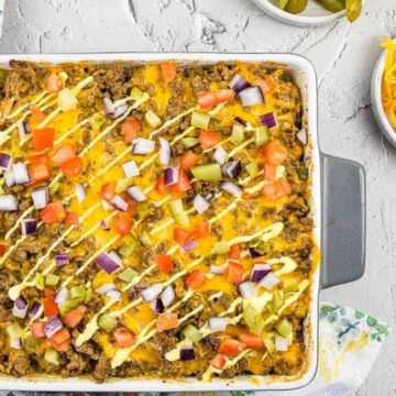 This square casserole dish is a show-stopper for potluck casseroles, featuring a layered taco creation topped with savory ground beef, chopped tomatoes, red onion, and cheese. A drizzle of sauce adds the perfect finish, while a bowl of shredded cheese and sliced jalapeños wait to wow the crowd.