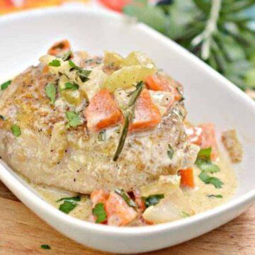 A dish reminiscent of Grandma's recipes features a piece of cooked meat topped with diced tomatoes, herbs, and a creamy sauce, served in a white oval dish. The background displays a colorful cloth and green leafy garnish.