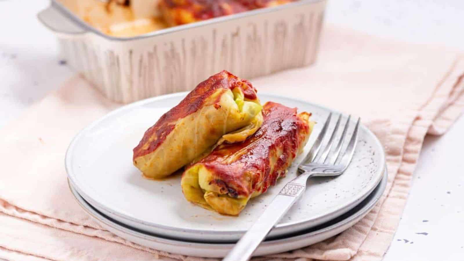 Two cabbage rolls on a plate with fork.