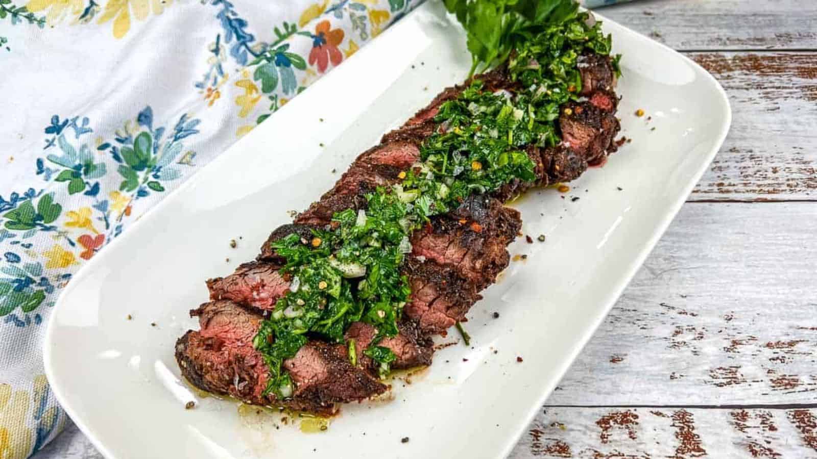 Sliced Grilled Hanger Steak with Chimichurri on a white plate.