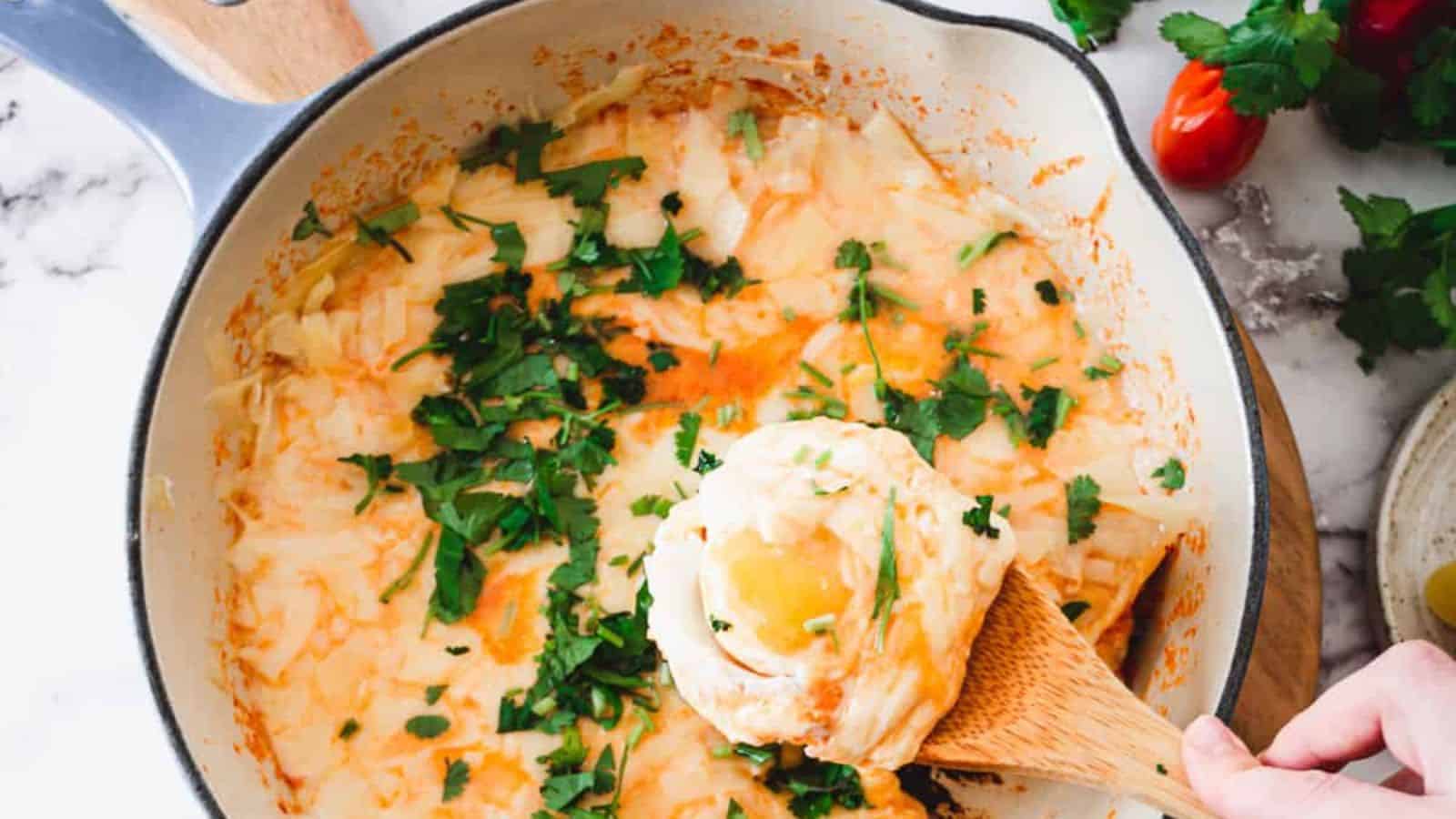 A pot of mouthwatering cheesy mashed potatoes topped with chopped herbs sits invitingly, with a wooden spoon resting within. Fresh herbs and tomatoes add a splash of color to the marble countertop. Ready in under 1 hour, this dish is perfect for entrees that leave everyone craving more.