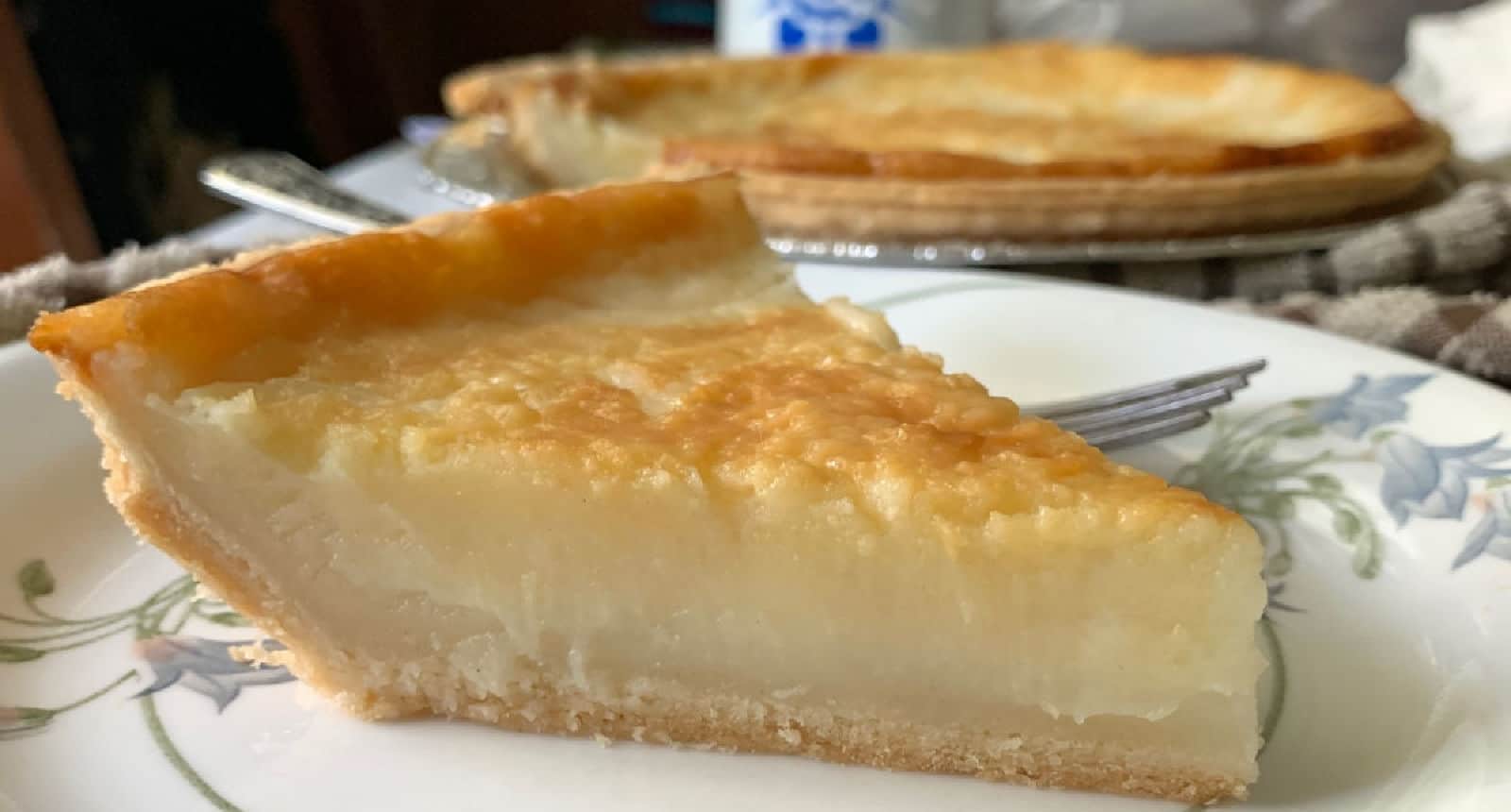 A slice of sugar cream pie on a white and floral plate.