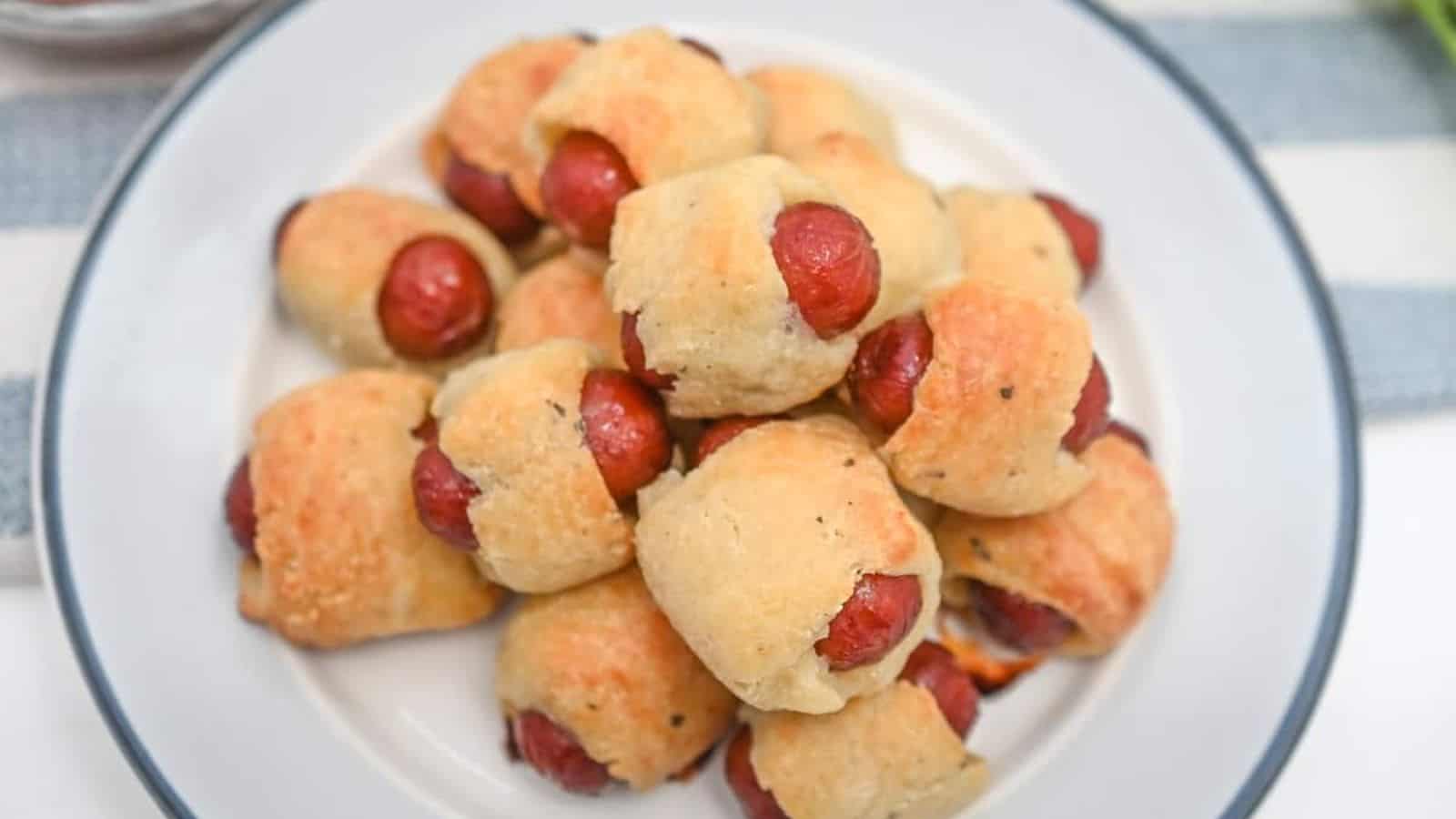 Hot dog buns with little smokies on a plate.