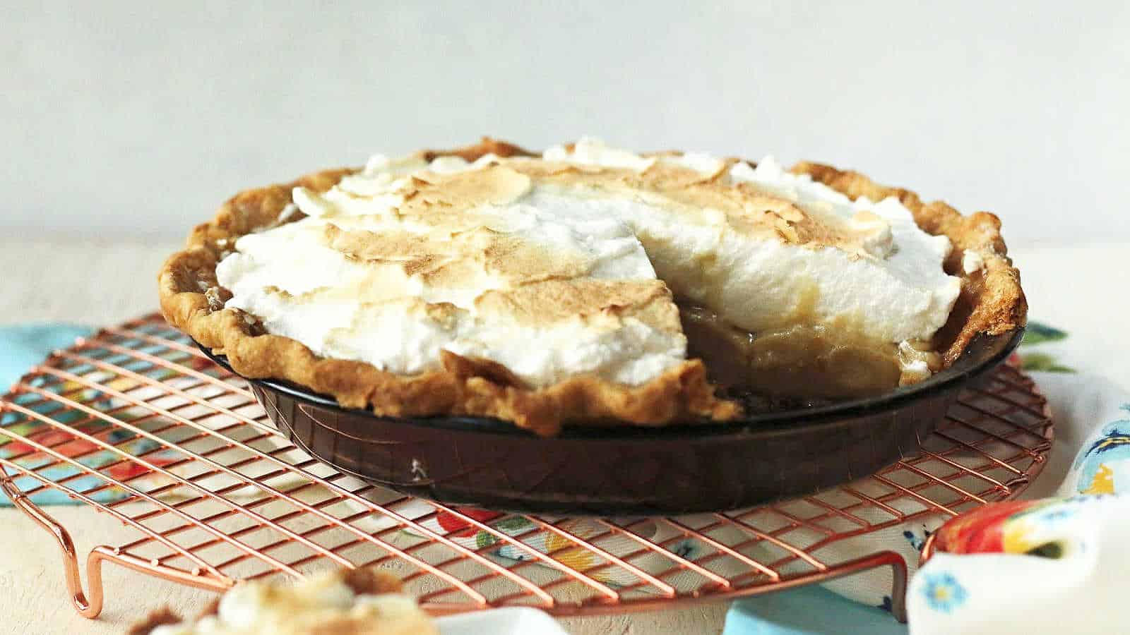 A butterscotch pie with meringue on a wire cooling rack.