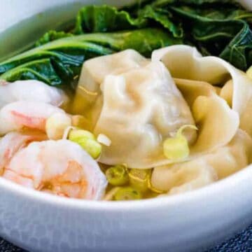 A bowl of wonton soup with shrimp in it.
