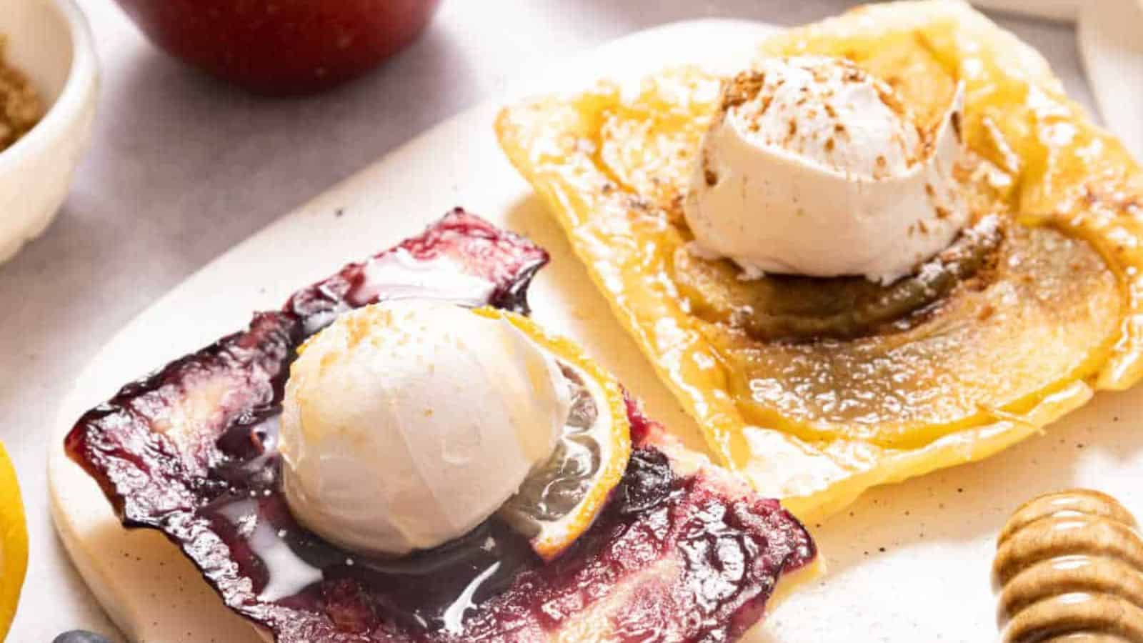 Puff pastry fruit tarts with apples and blueberries on a white board.