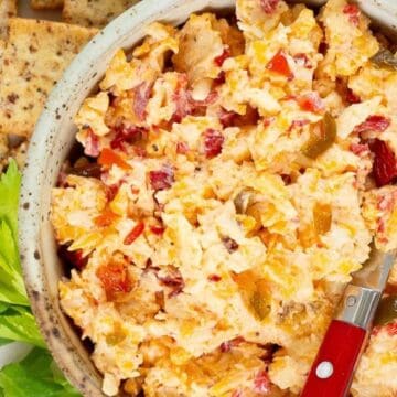 A bowl of spicy pimento cheese dip with crackers on the side.