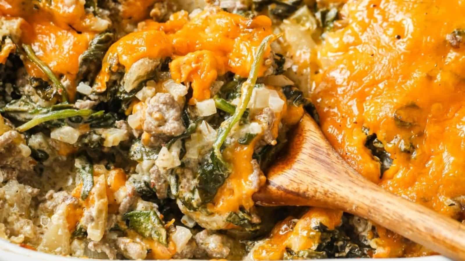 Image shows a closeup of a spoon holding some Cheesy Beef and Rice Casserole with the full skillet behind it.