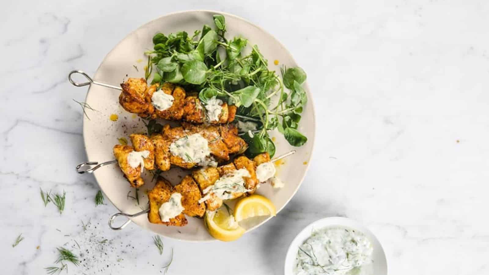 A plate of shawarma kebabs with greens and lemon slices.