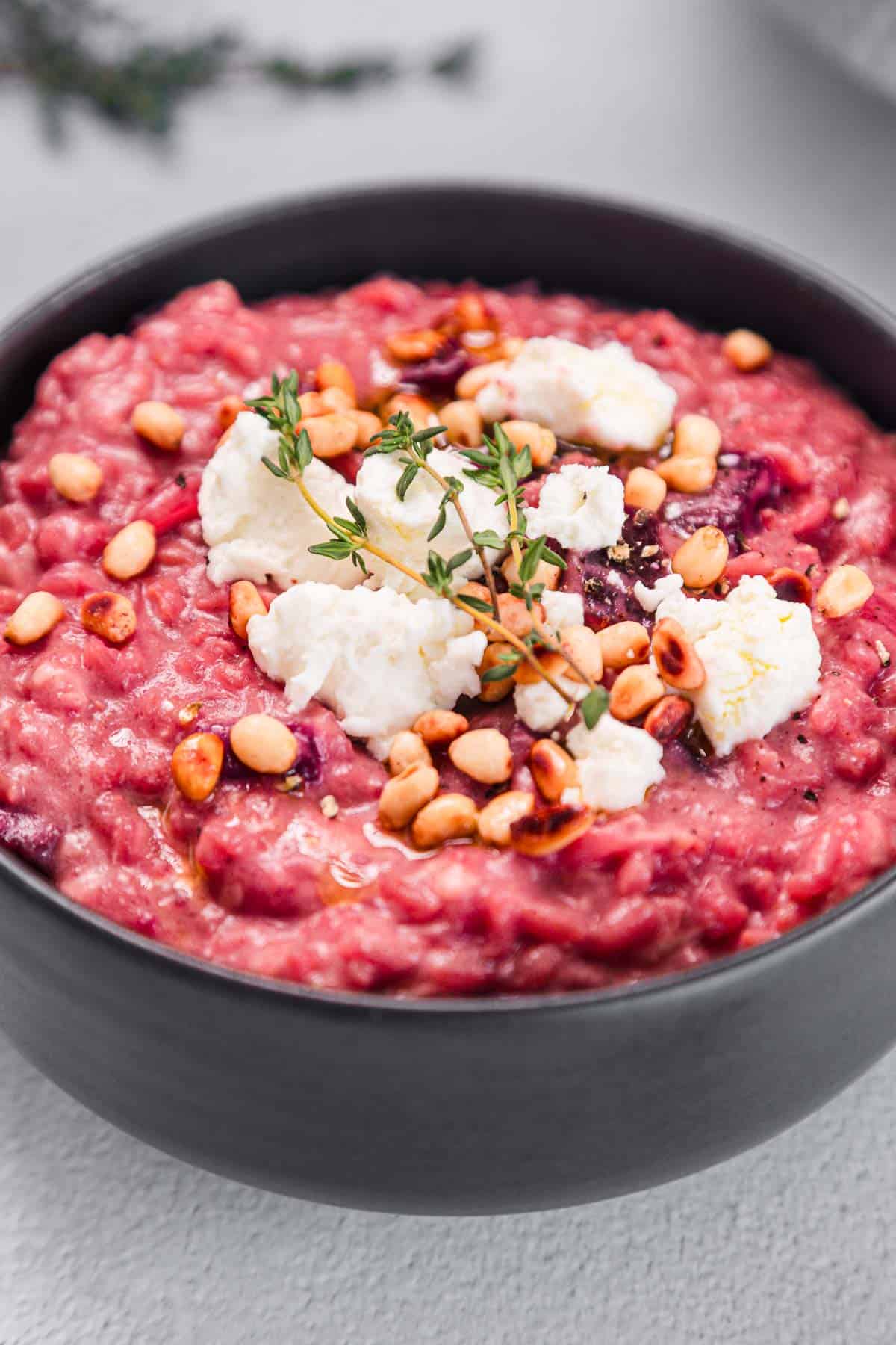 A bowl of red rice with cheese and herbs.