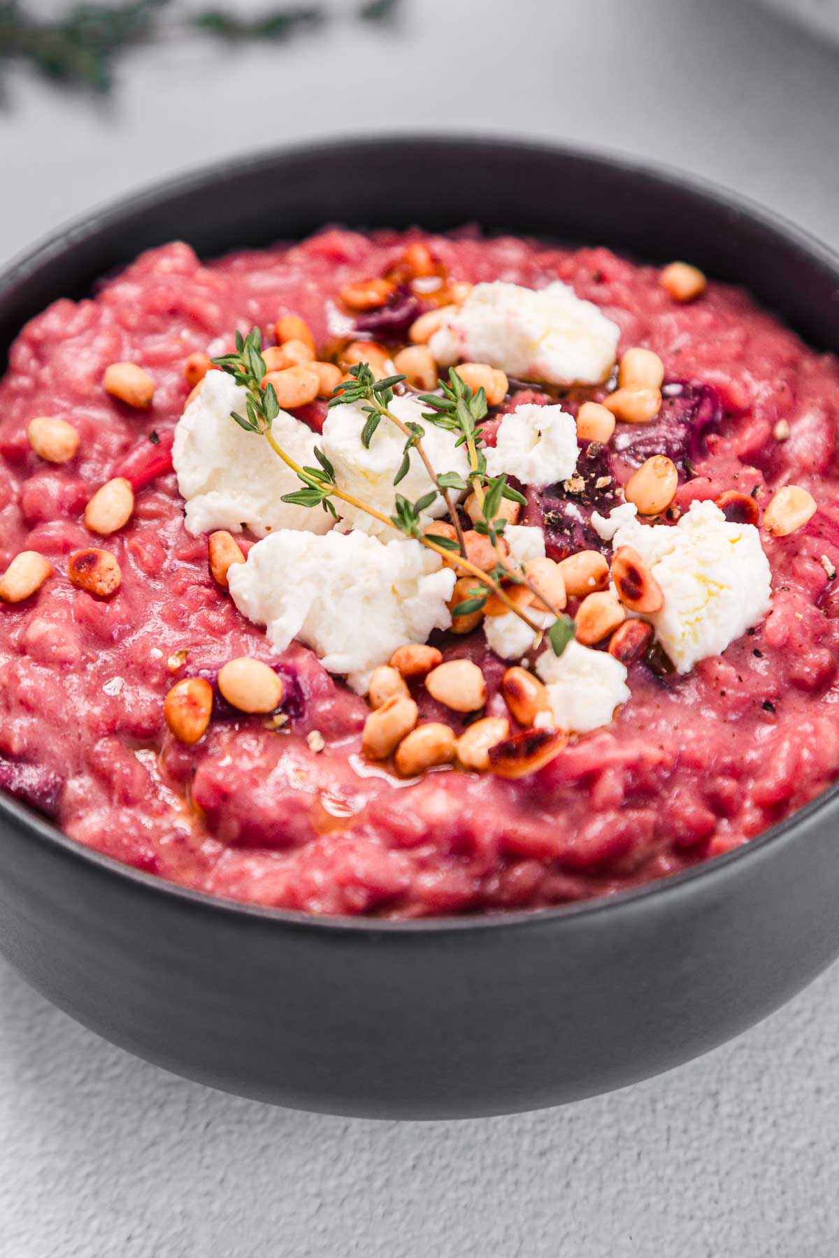 A bowl of red rice with cheese and herbs.