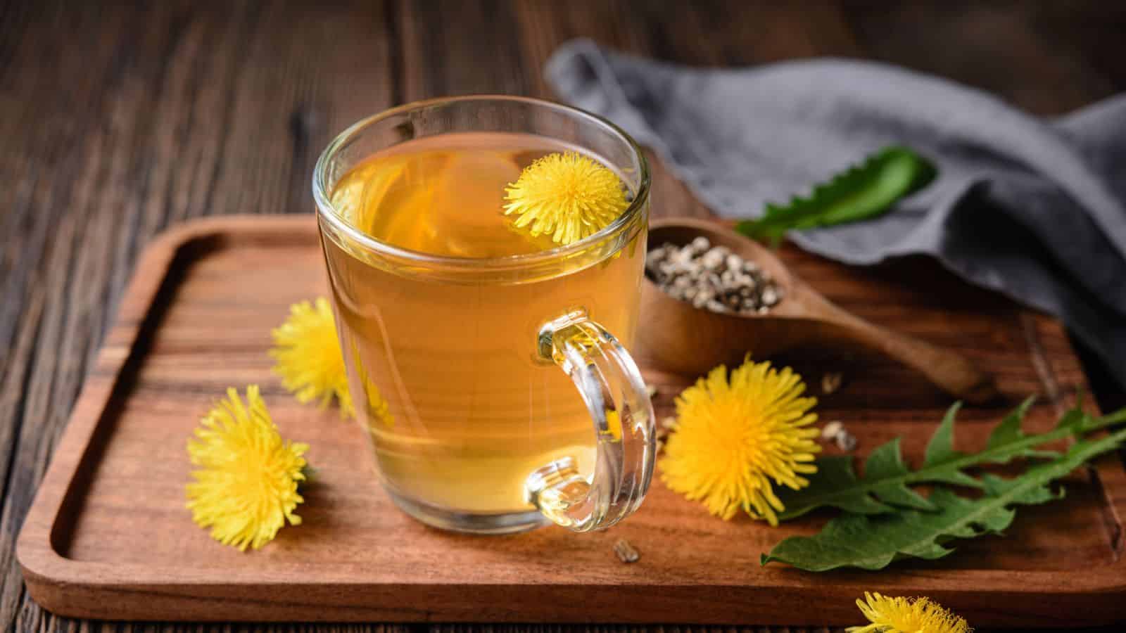A cup of dandelion tea on a counter with a mason jar of tea and a spoon with honey.