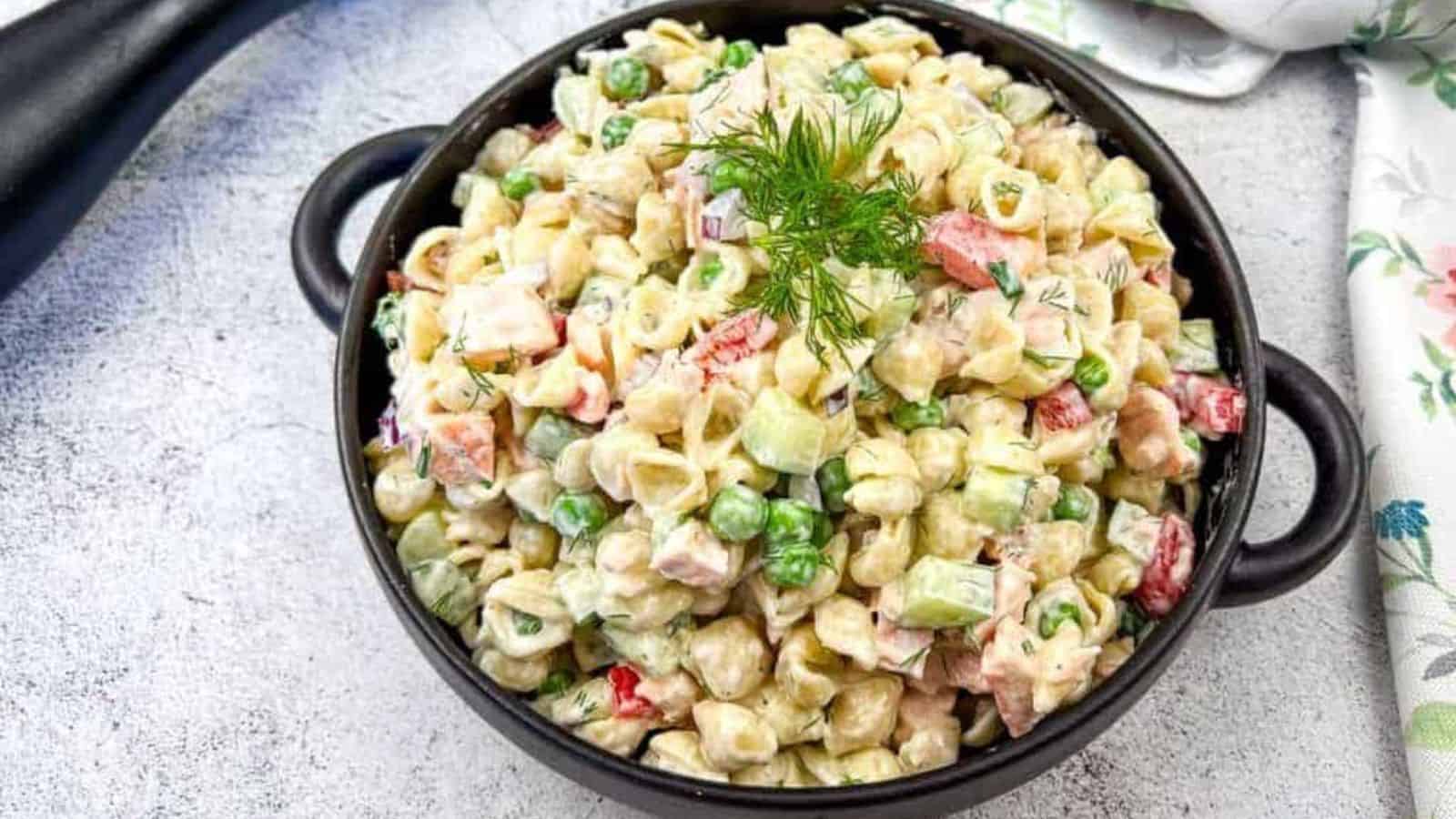 Salmon pasta salad in a black bowl with forks nearby.