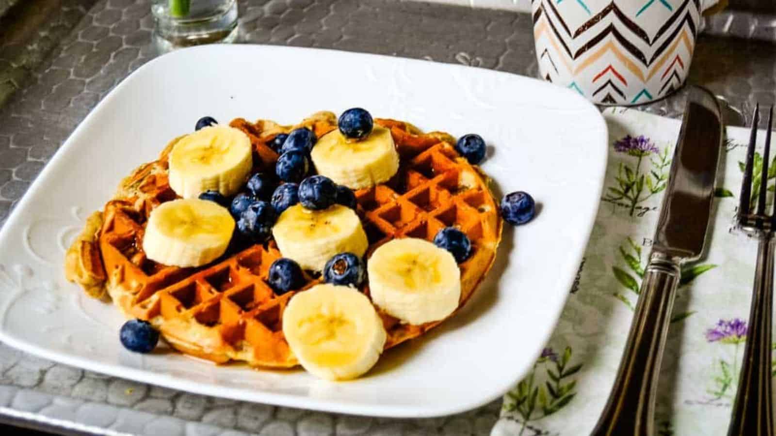 A plate of banana waffles with bananas and blueberries.