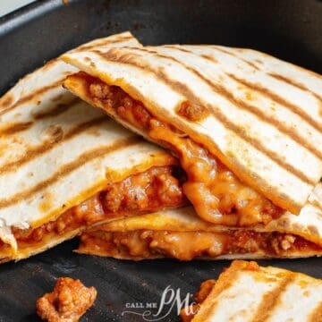 Three grilled quesadillas filled with melted cheese and seasoned ground meat are stacked on a black griddle pan. Some filling has spilled onto the pan. The quesadillas have golden-brown grill marks.
