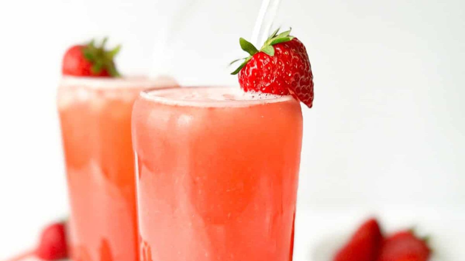 Two glasses of strawberry green tea drink, each topped with a strawberry.