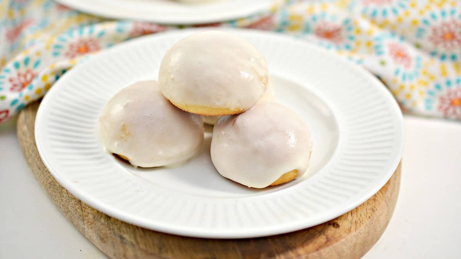 Three glazed donuts on a white plate.