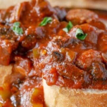 Two slices of bread topped with a rich, chunky tomato-based meat and vegetable stew, garnished with herbs—a comforting classic inspired by boomer recipes.