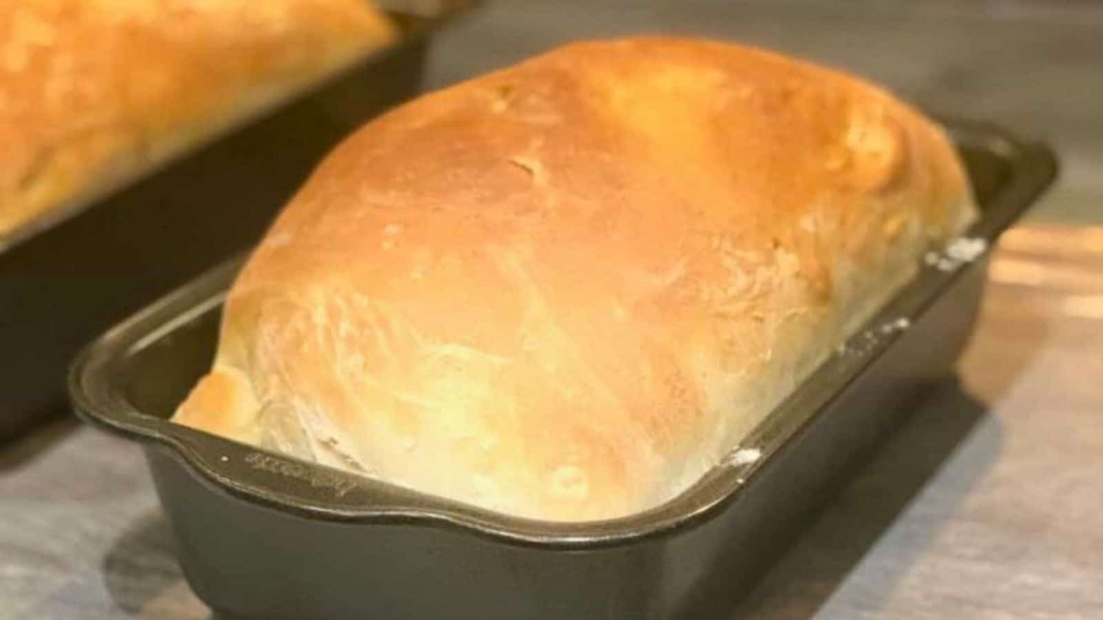 Homemade sandwich bread cooling in a loaf pan.