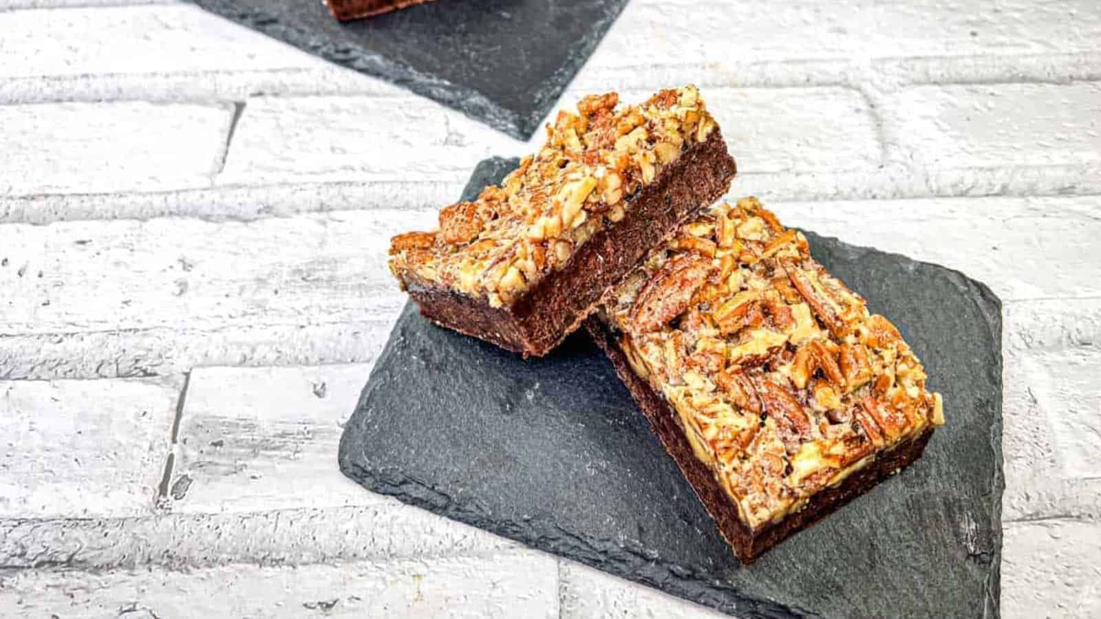 Three pieces of pecan pie brownies on slate coasters.
