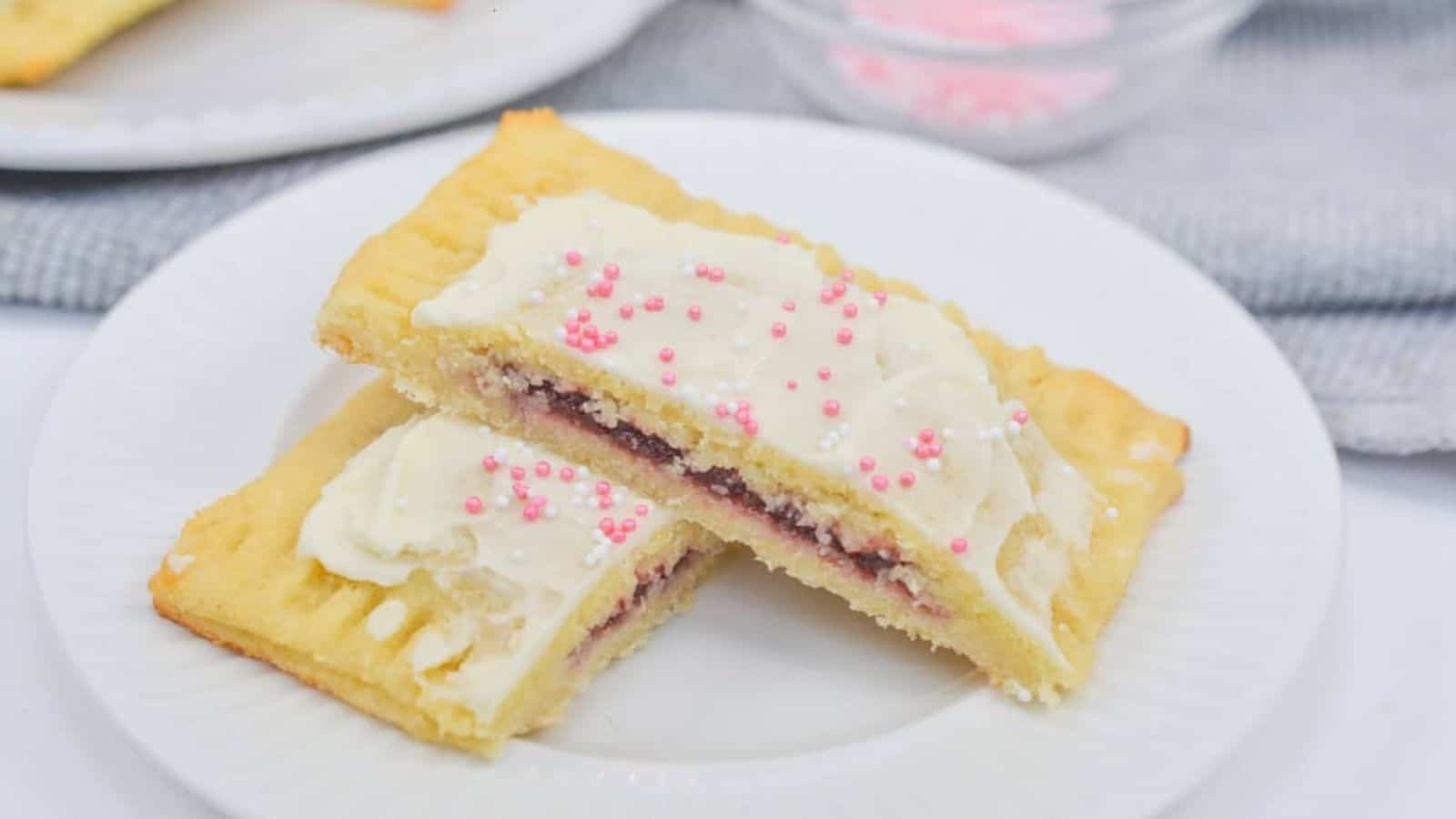 A plate with a slice of a cookie with frosting and sprinkles.