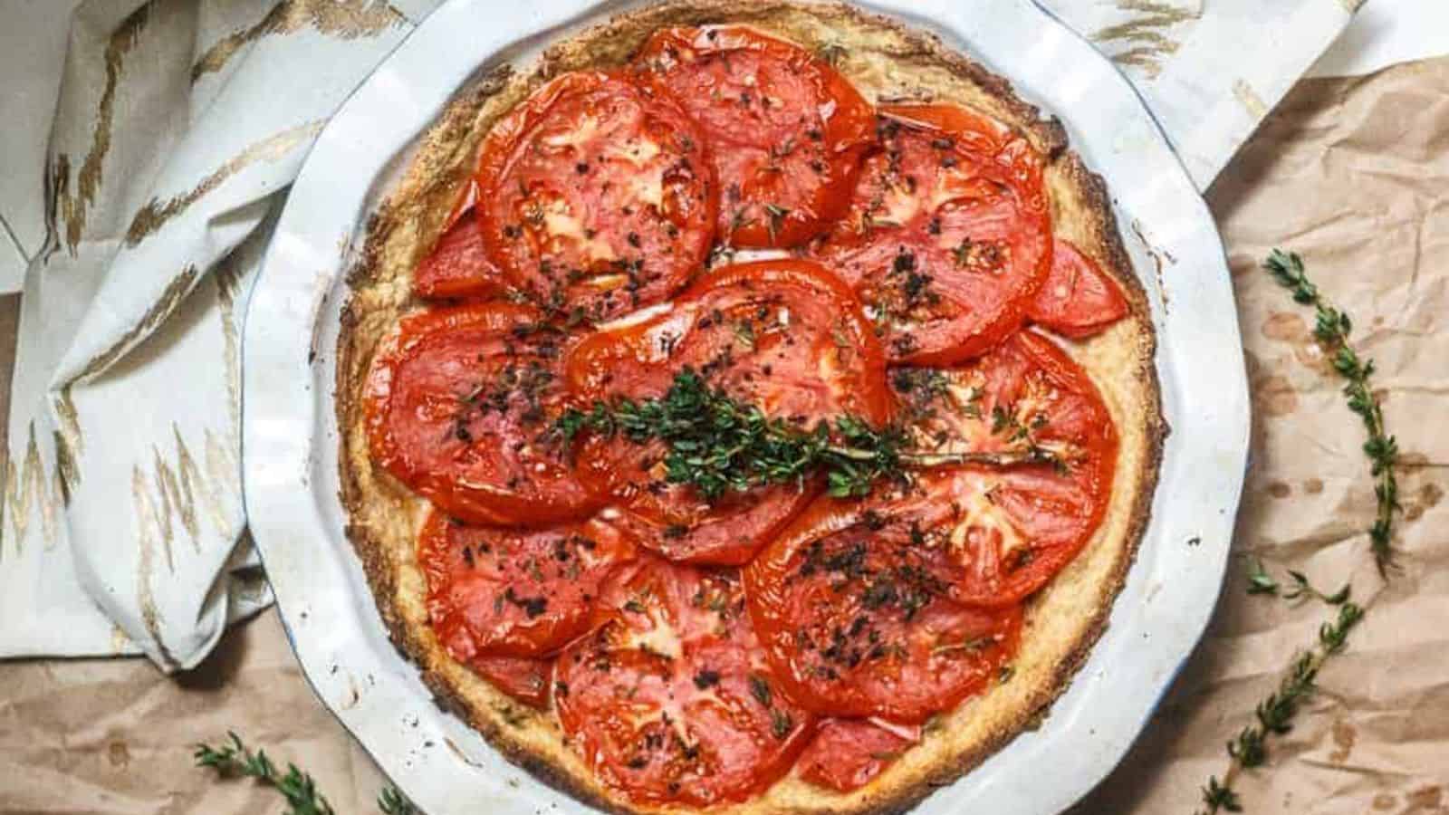 A pie with tomatoes and thyme on top.