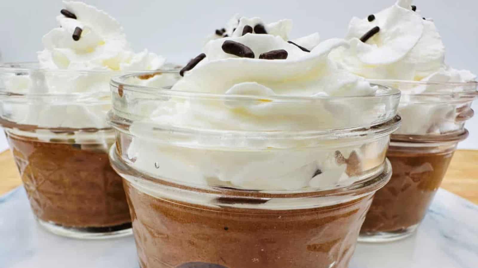 Chocolate mousse in mason jars with whipped cream and chocolate chips.