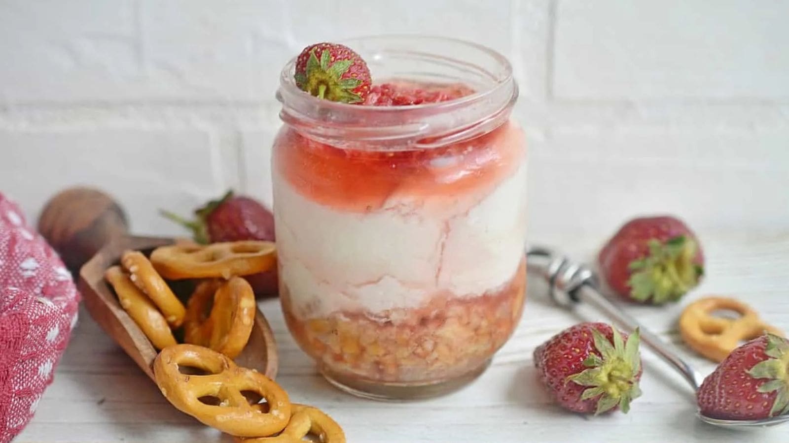 Jar of dessert with strawberries and pretzels.