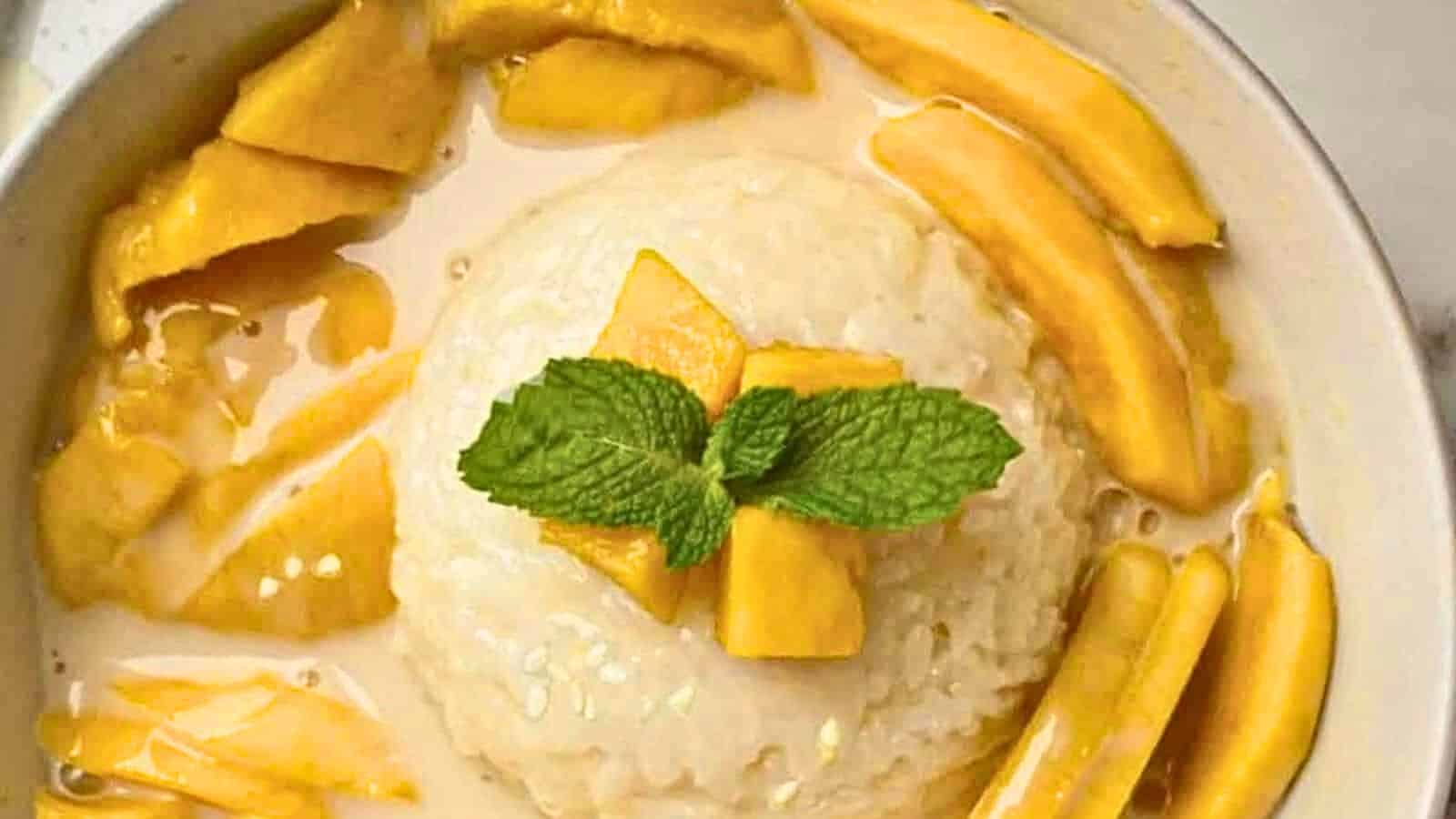 A bowl of mango sticky rice garnished with mint leaves.