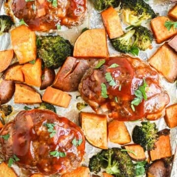 A baking sheet lined with foil holds three glazed meatloaf portions, surrounded by roasted sweet potato cubes and broccoli florets. A yellow and white towel is partially visible to the left.
