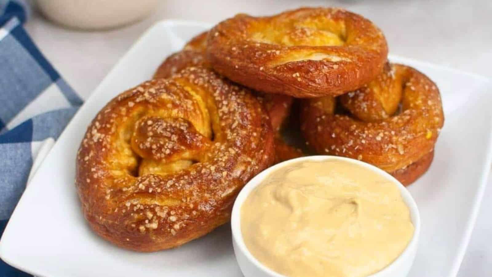 Five sourdough soft pretzels stacked on a plate.
