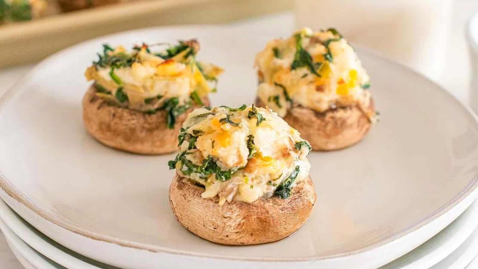 Three stuffed mushrooms filled with a cheesy spinach mixture are served on a white plate, making them perfect go-to appetizers for any gathering.