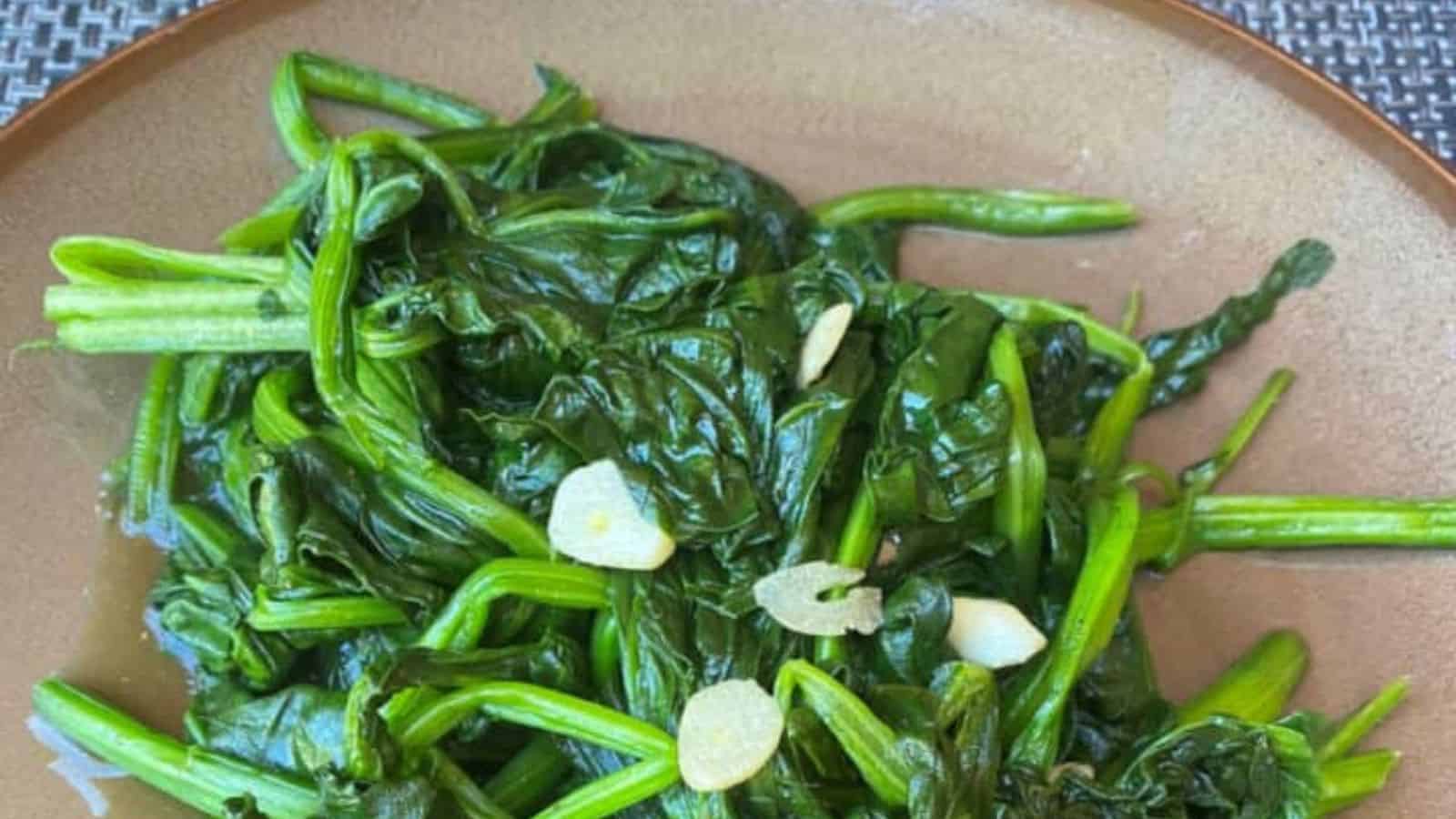 Healthy and flavorful stir-fried Taiwanese spinach with garlic on a brown plate.
