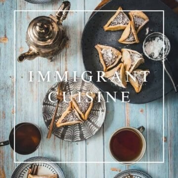 A table set with tea, teacups, a patterned plate with pastries, a metal teapot, a plate with powdered pastries, and a small bowl of powdered sugar. Text over the image reads "Immigrant Cuisine.