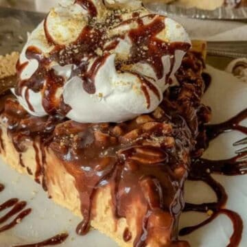 A slice of chocolate pie topped with whipped cream and chocolate drizzle on a white plate with a fork.
