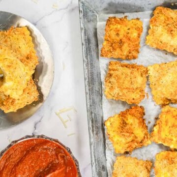 Baked ravioli on a tray with marinara sauce, and two pieces served on a small plate with sauce.