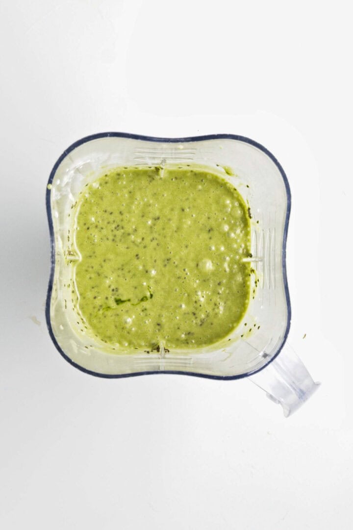 A blender filled with a vibrant green smoothie or sauce, possibly for Banana Matcha Chia Pudding, viewed from above on a white background.