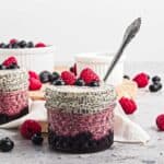 Berry Chia Pudding layered in a glass jar, topped with fresh raspberries and blueberries, with a spoon inside for easy serving.