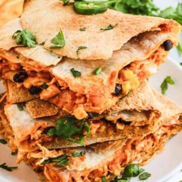 Stack of chicken quesadilla wedges with cilantro garnish.