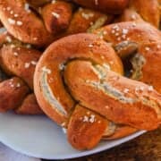 A plate of gluten-free soft pretzels topped with coarse salt, served on a white dish.