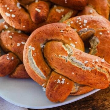 A plate of gluten-free soft pretzels topped with coarse salt, served on a white dish.