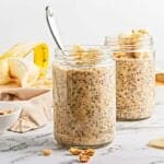 Two jars of Peanut Butter Banana Overnight Chia Oats, topped with banana slices and peanuts, make a delicious and wholesome breakfast.