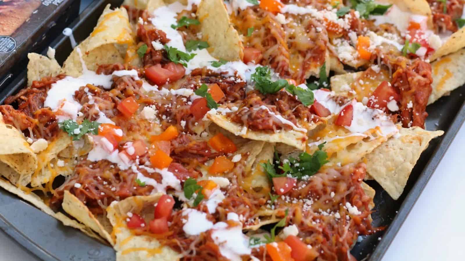 Sheet pan of nachos - topped with pulled pork, cheese, veggies, etc.